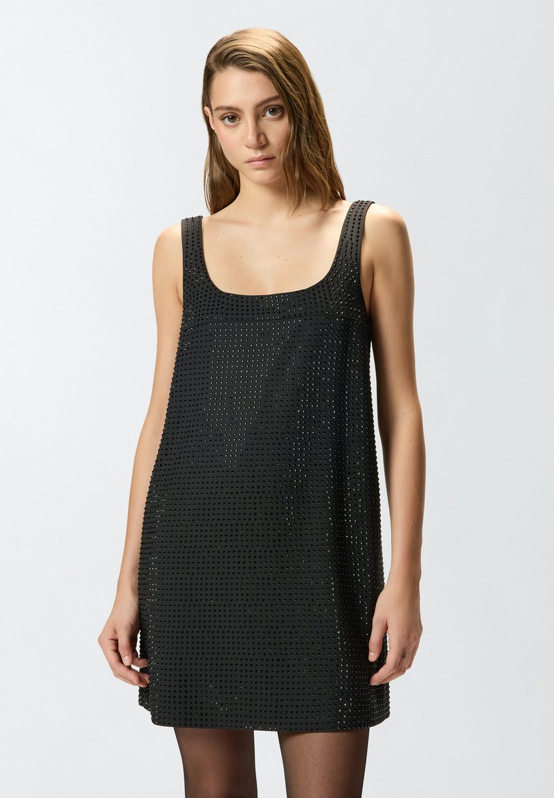 Vestido negro sin mangas con escote cuadrado bien definido, patrón texturizado de pequeños agujeros y corte recto. Tejido suave con un brillo sutil.