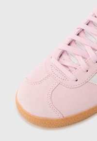 Rosa mockasin sneaker med rund tå, texturerad gummisula och matchande rosa snörning. Har vitt detaljer på sidan.