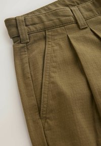 Olive green pleated pants made of textured fabric. Features a waistband with belt loops and stitching detail along the seams.