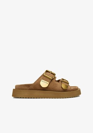 Sandalia tipo slide de ante marrón con dos hebillas doradas ajustables y una suela gruesa con relieve.