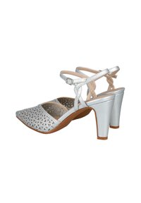 Sandalias plateadas con tacón, con un diseño perforado en la parte del dedo del pie, correa ajustable en el tobillo y un tacón cónico. Textura suave y material sintético.