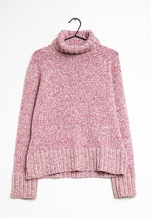Pull à col roulé en maille marbrée rose et blanche suspendu sur un cintre noir contre un fond blanc.