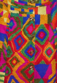 Kleurvolle geweven stof met een geometrisch patroon van vierkanten en diamanten in rood, groen, geel, blauw en roze, verfraaid met bruine knopen.