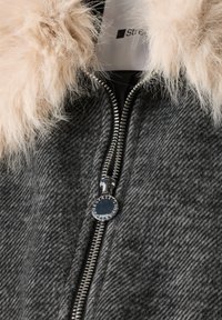 Gros plan d'une veste gris foncé texturée avec une fermeture éclair argentée et un col en fourrure beige clair et duveteux.