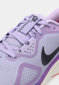 Αθλητικό παπούτσι σε ανοιχτό μωβ χρωματισμό με υφή στην επιφάνεια, μαύρο σήμα Nike και μωβ λεπτομέρειες. Διαθέτει αναπνεύσιμο πλέγμα και επενδεδυμένη γλώσσα.