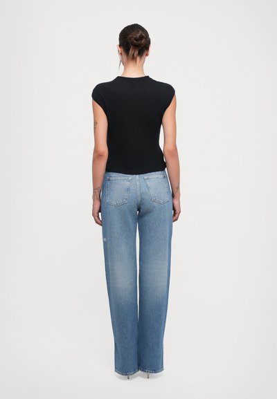 Black fitted top with cap sleeves, paired with light blue wide-leg jeans featuring a faded finish and two back pockets.
