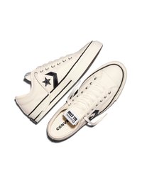 Een paar witte lage Converse sneakers met zwart sterlogo, witte veters en rubberen zolen op een witte achtergrond.