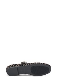 Zapato con tiras, parte superior de gamuza a rayas negras y beiges, punta redonda, detalle de hebilla plateada y suela de goma texturizada negra.