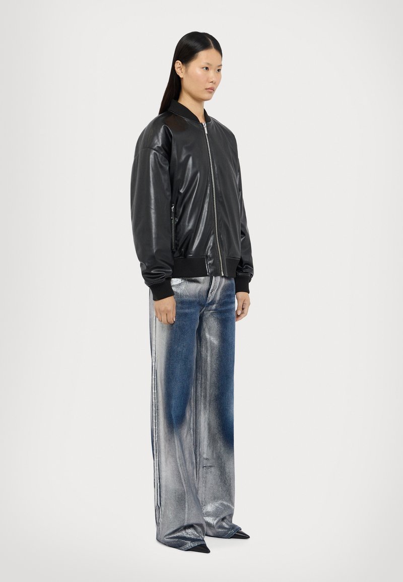 Svart läderbomberjacka med ribbade manschetter och fåll, kombinerad med vida metallicblå jeans. Skorna har en spetsig tådesign.
