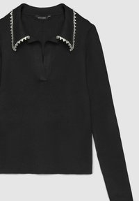Schwarzes gestreiftes Langarmshirt mit einem Kragen, der mit Kristallverzierungen entlang der Kante versehen ist, und einer Öffnung mit Knopfleiste vorne.