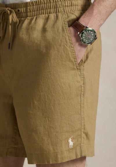Χακί λινά σορτς με ελαστική μέση και πλαϊνές τσέπες, με μικρό λευκό κεντητό λογότυπο στο τελείωμα.