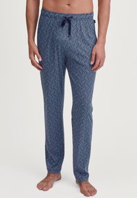 Marineblauwe pyjamabroek met een geometrisch wit patroon. Gemaakt van zacht materiaal, met een elastische tailleband met een trekkoord en rechte pijpen.