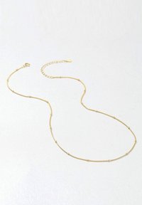 Collier en ton or présentant une chaîne délicate avec de petites perles rondes, un fermoir à homard et une petite chaîne d'extension pour un ajustement de la longueur.