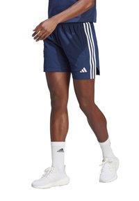 Marine atletische shorts met drie witte strepen aan de zijkanten, elastische tailleband, gedragen met witte sokken en schoenen. Gladde stofstructuur.