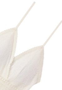 Bralette bianco in pizzo con coppe triangolari, delicate rifiniture a scalloped e sottili spalline regolabili. Presenta un motivo floreale sul tessuto.