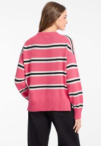 Übergroßer pinker Pullover mit schwarz-weißen horizontalen Streifen, geripptem Saum und Abschlüssen, weichem Strickmaterial und mit lockerer Passform.