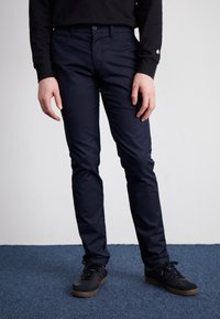 Námořnické modré, slim-fit kalhoty vyrobené z odolné látky. Mají zipový přední díl, přední kapsy a hladkou strukturu. Nosit s černými teniskami.
