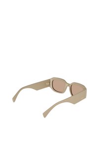 Ανοιχτό μπεζ γυαλιά ηλίου με γωνιώδη σκελετό, επίπεδους φακούς και φαρδιά μπράτσα. Η υφή είναι ματ με ελάχιστη σήμανση στους βραχίονες.