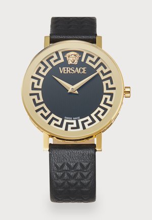 Kullatoon kell, millel on must tekstureeritud nahkrihm. Must kellaplaat sisaldab Kreeka võtme mustrit ja lõvi pea embleemi, millel on märge "Šveitsi tootmine".