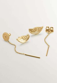 Pendientes en tono dorado con diseños de alas, uno con un acento de cadena y barra, y el otro con un Stud redondo, que exhiben un detallado intrincado.