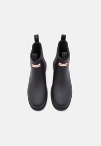Μαύρες ankle μπότες από καουτσούκ με λεία υφή. Διαθέτουν λογότυπο στο πλάι, χερούλια και στρογγυλή σχεδίαση δαχτύλου.