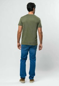 Olive žalios spalvos trumpomis rankovėmis marškinėliai, aptempto dizaino, derinami su mėlynais džinsais. Paprastas stilius, minkšta tekstūra, matomos siūlės ir kasdieniškas vaizdas.