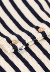 Pullover a righe crema e blu navy con un tessuto a maglia testurizzata, dotato di due bottoni in legno e di una piccola etichetta con marchio vicino al colletto.