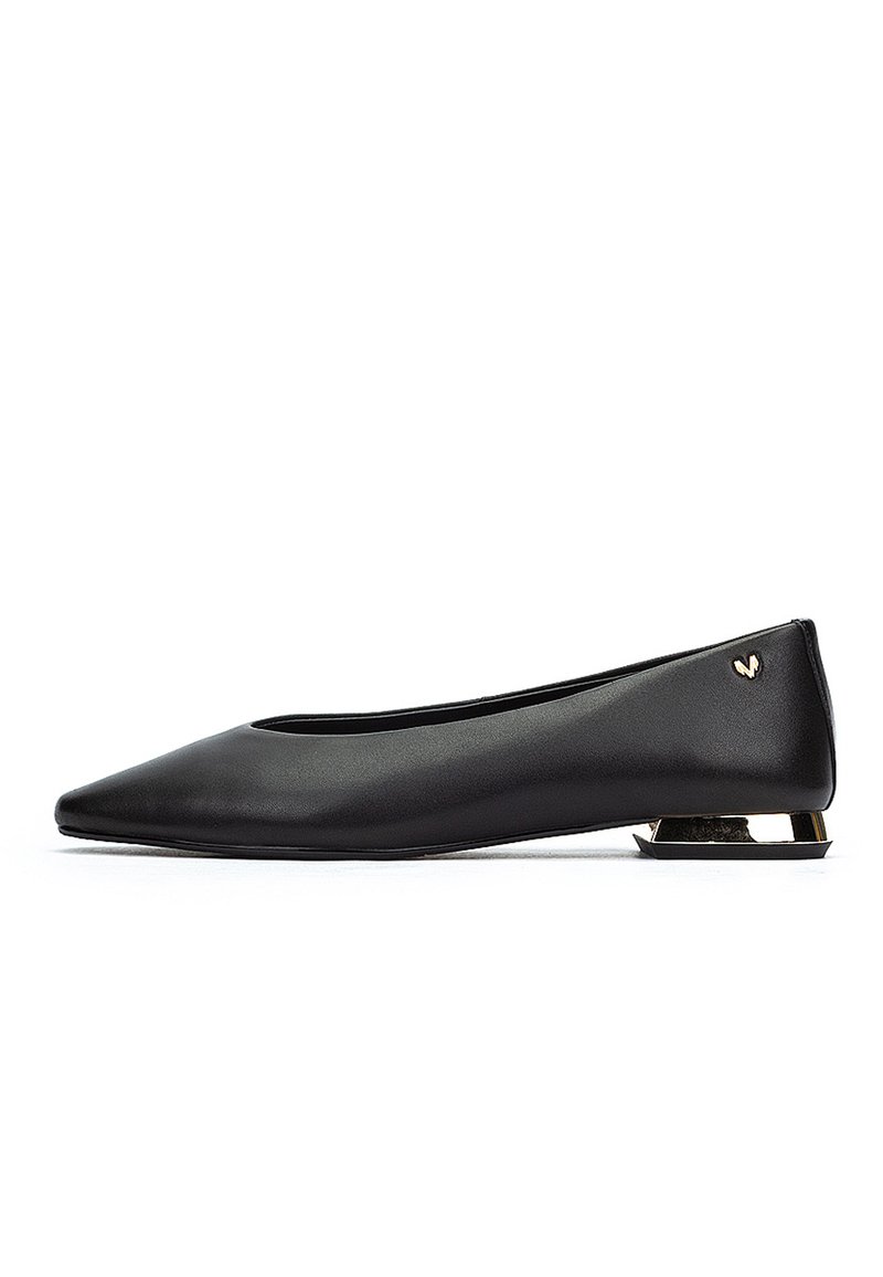 Zapato plano negro de punta con un bajo tacón de bloque metálico dorado y un pequeño emblema dorado cerca del tacón.