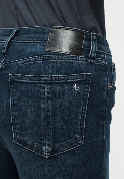 Σκούρο μπλε τζιν με λεπτομέρειες ραφής στην πίσω τσέπη και μαύρη δερμάτινη ετικέτα με την επωνυμία «& bone New York» στη μέση της ζώνης.