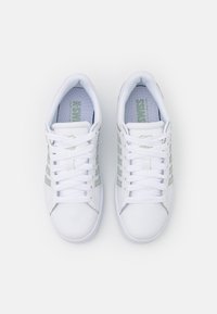 Sneakers bianchi con dettagli verdi, realizzati in materiale sintetico. Presentano lacci, fodera in rete e tre strisce su ciascun lato. Design a suola piatta.