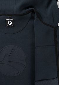 Hoodie bleu marine avec un patch logo de montagne texturé et des finitions noires contrastantes. Le matériau semble doux et flexible, avec des poches latérales.