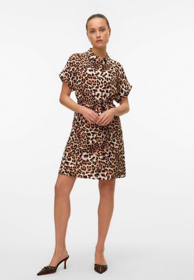 Abito corto con stampa leopardata, tessuto leggero, stile con bottoni, maniche corte, vita attillata. Indossato con tacchi a punta, texture liscia.