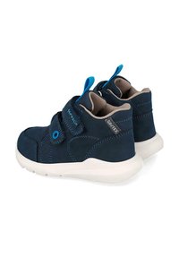 Zapatillas infantiles de color azul marino con suelas blancas, cintas de velcro, tiradores azules y etiqueta de tela Grutex en el talón.