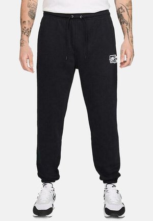 Schwarze Sweatpants mit einem Kordelzug-Bund, seitlichen Taschen, gerippten Bündchen und einem kleinen weißen Logo auf dem linken Oberschenkel. Weicher Stoff.