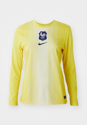 Ilgi piedurkņu Nike krekls spilgti dzeltenā krāsā ar vertikālām svītrām, kurā ir zilā emblēma ar gaili un melns swoosh logo.