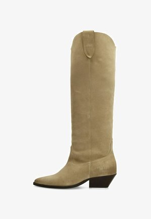 Beige suede knee-high boot with a pointed toe, slightly stacked heel, and a looped accent at the top. Smooth texture with minimal stitching.
