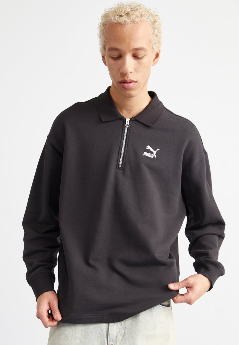 Zwarte pullover met een rits in de nek, lange mouwen en een subtiele Puma-logo op de linkerborst. Gemaakt van zacht, textuurstof.