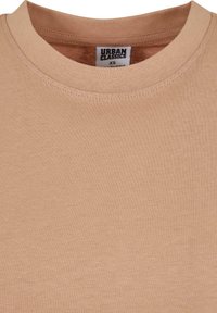 Béžové bavlněné tričko s kulatým výstřihem, hladkou texturou a jemnými švy; štítek čte "URBAN CLASSICS," velikost XS.