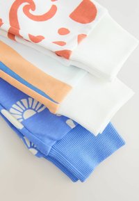 Vier Paare bunter Baumwollmanschetten: weiß mit orangefarbenem Muster, hellblau, pfirsichfarben mit blauen Streifen und blau mit weißem Sonnendesign.