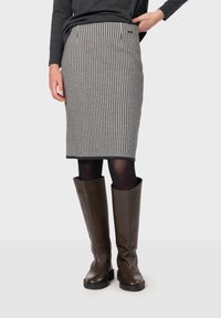 Grå och svart houndstooth-mönstrad blyertskjol med framfickor och rak snitt, i kombination med knähöga bruna läderstövlar.