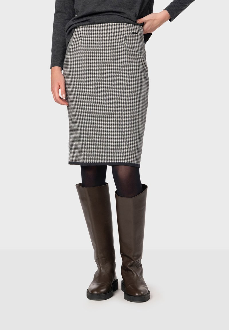 Grå och svart houndstooth-mönstrad blyertskjol med framfickor och rak snitt, i kombination med knähöga bruna läderstövlar.