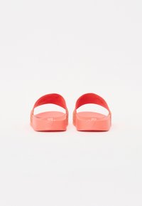 Korallfärgade flip-flops med två breda, böjda remmar och en texturerad sula. Remmarna har en nätliknande design för andningsförmåga.