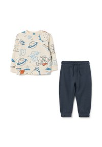 Haut à manches longues beige clair avec des imprimés de dessins animés, associé à un pantalon de jogging tapered bleu foncé avec une taille élastique.