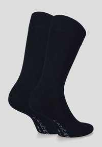 Czarne skarpetki o gładkiej fakturze, sięgające do połowy łydki, z prążkowanymi mankietami i małym białym logo na dole. Prosty i jednolity design.