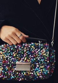 Mångfärgad paljetthandväska med en svart bas, rektangulär form, silverfäste och kedjestropp. Paljettfärgerna inkluderar blå, grön och rosa.
