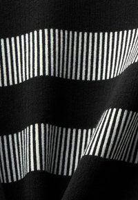 Tissu noir avec deux bandes blanches horizontales, chacune composée de lignes blanches verticales rapprochées.