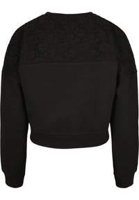 Sweat-shirt court noir à manches longues avec détails en dentelle sur le haut du dos et les épaules, poignets et ourlet côtelés.