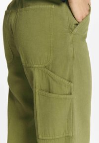 Groene katoenen cargo-broek met meerdere zakken en zichtbare stiksels. De stof lijkt duurzaam met een soepele textuur.