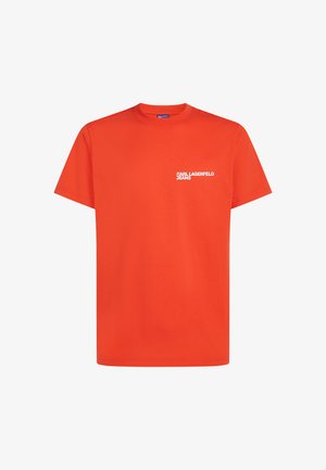 Oranžist puuvillast T-särk, millel on lühikesed varrukad ja ümar kaelus. Vasakul rinnal on valge tekst "KARL LAGERFELD JEANS".