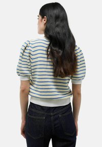 Pull à manches courtes rayé bleu et jaune, tricot texturé, avec des manches bouffantes et un ourlet côtelé blanc, porté avec un jean sombre.